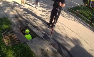 Illustration de l'article : Tomb&eacute; dans un &eacute;gout, un chien est secouru par des policiers et un agent des services publics puis rendu &agrave; son propri&eacute;taire (vid&eacute;o)