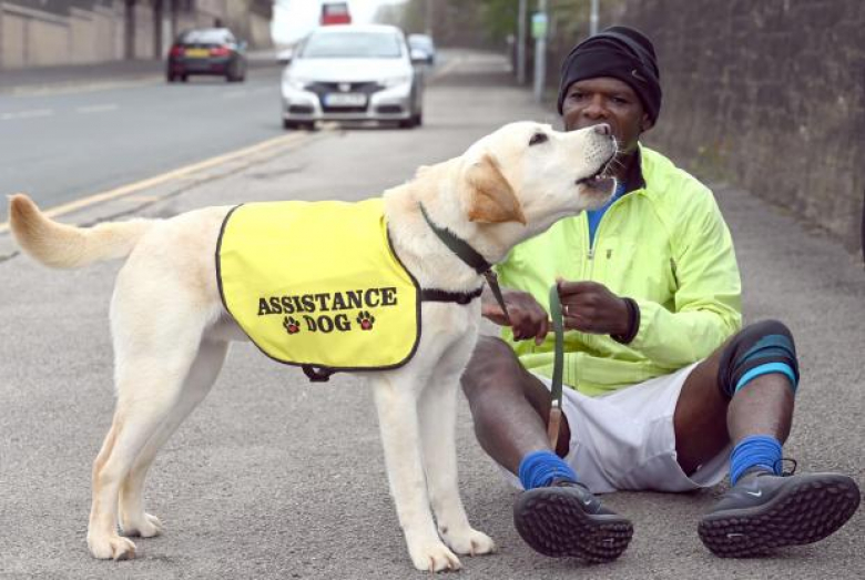 Brian assis sur la chaussée, Loki en gilet d'assistance lui léchant le visage © Telegraph & Argus