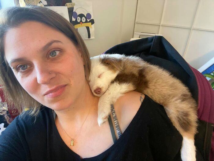 Une femme fait un selfie avec un chiot endormi sur son épaule