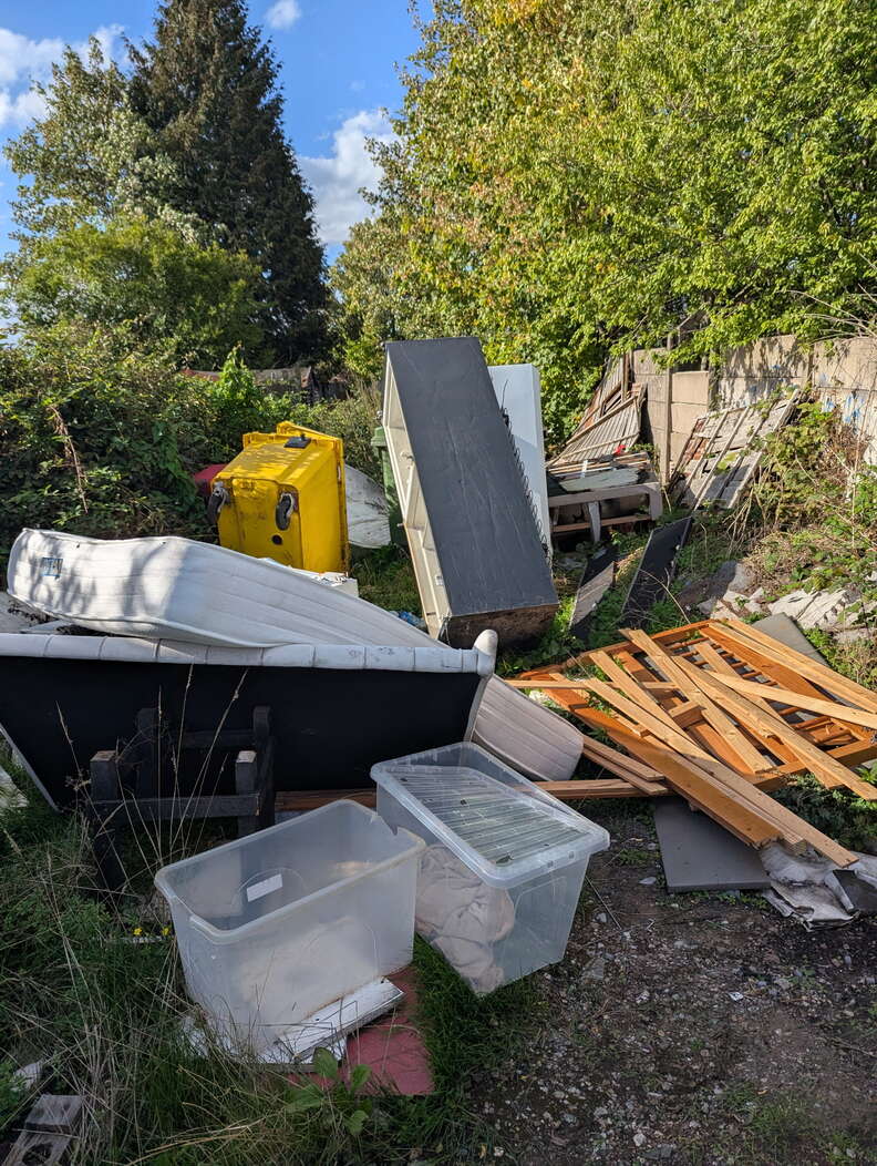 Un tas d'encombrants, matelas et planches cassées, avec deux bacs transparents au premier plan