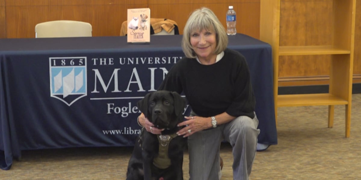 Claire Hebert-Dow accroupie et souriante derrière Bear, grand chien noir en harnais vert