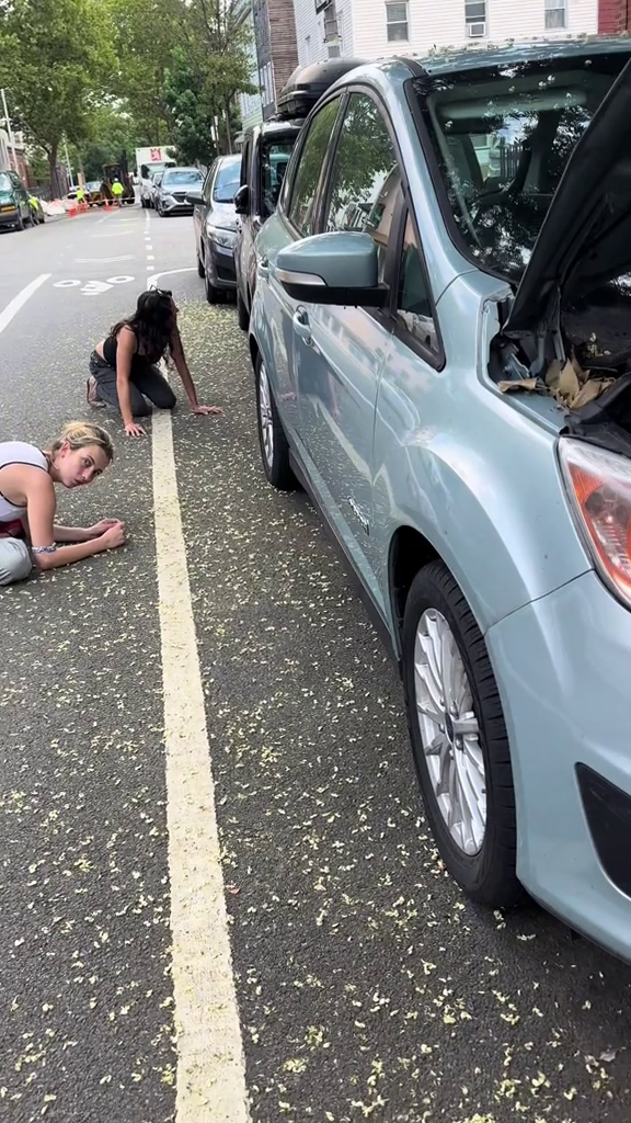 Deux jeunes femmes accroupies regardent sous la voiture