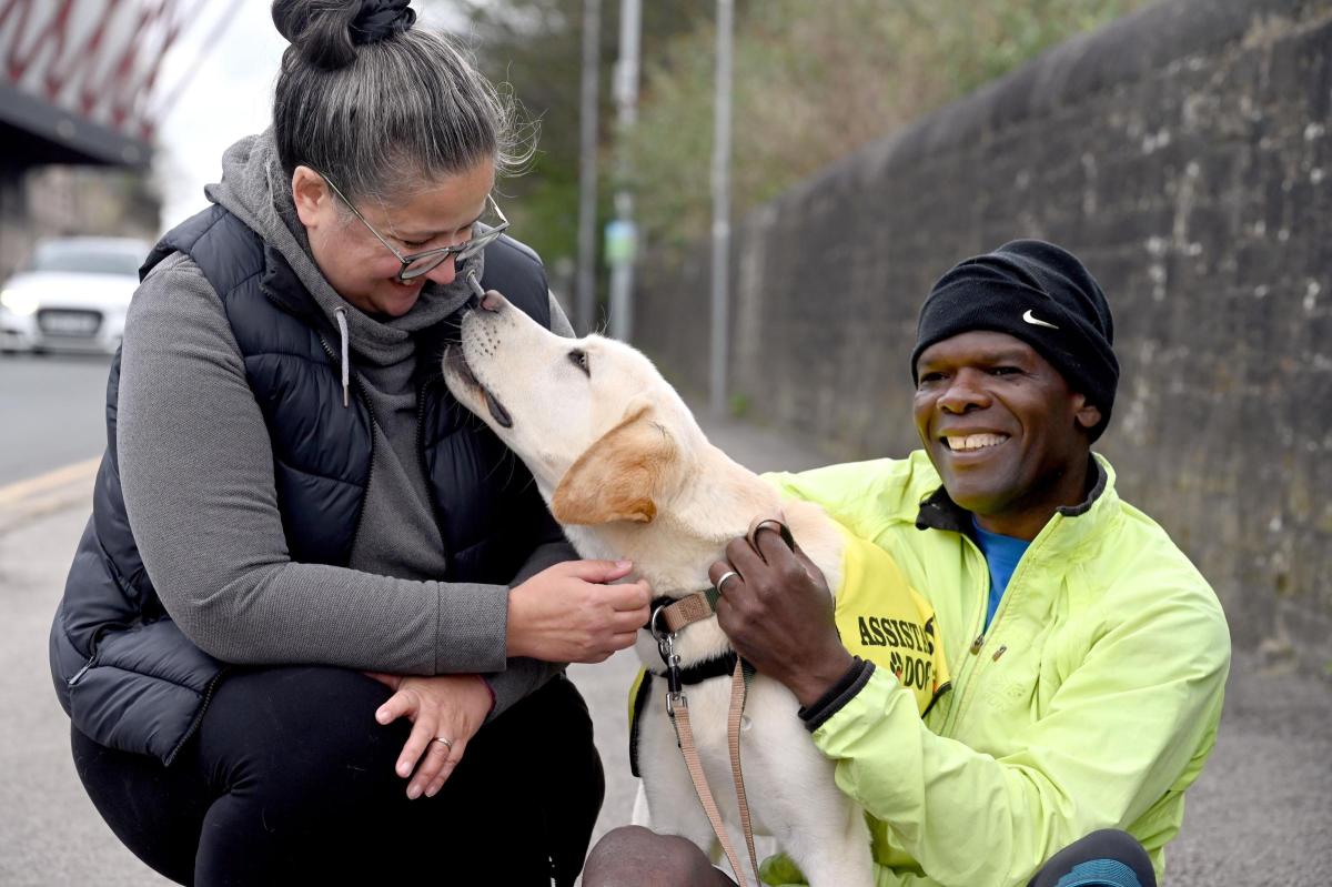 Keely et Brian accroupis sur le trottoir, souriants, caressant Loki