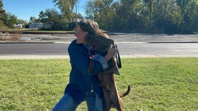 Une participante serre dans ses bras un chien brun dressé sur ses pattes arrière